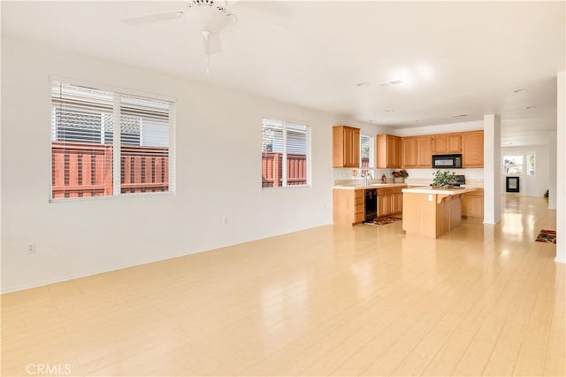 kitchen with ceiling fan, a healthy amount of sunlight, a breakfast bar area, and black appliances