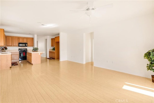 kitchen with stove, sink, light hardwood / wood-style floors, and ceiling fan