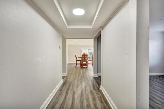 corridor featuring hardwood / wood-style flooring and a raised ceiling