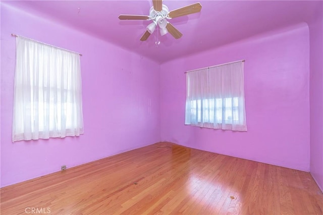 empty room featuring wood-type flooring, plenty of natural light, and ceiling fan