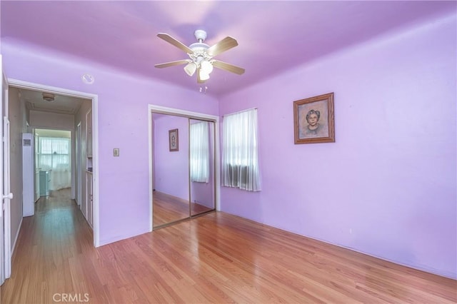 unfurnished bedroom with light hardwood / wood-style flooring, a closet, and ceiling fan