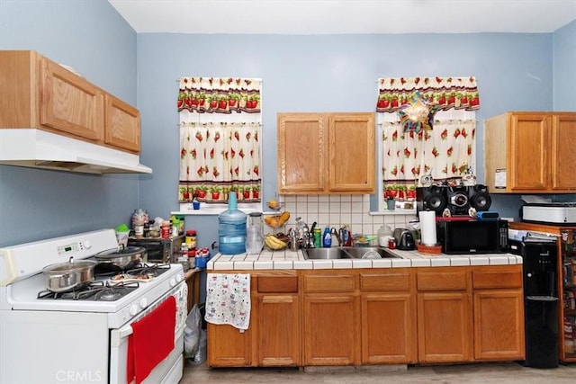 kitchen featuring tile counters, white range with gas cooktop, sink, and decorative backsplash