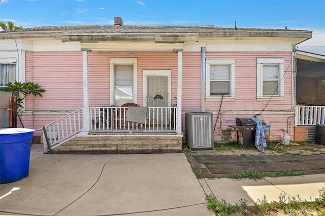 doorway to property with cooling unit, covered porch, and a patio