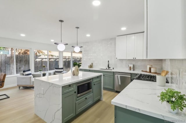 kitchen featuring appliances with stainless steel finishes, pendant lighting, sink, white cabinets, and green cabinets