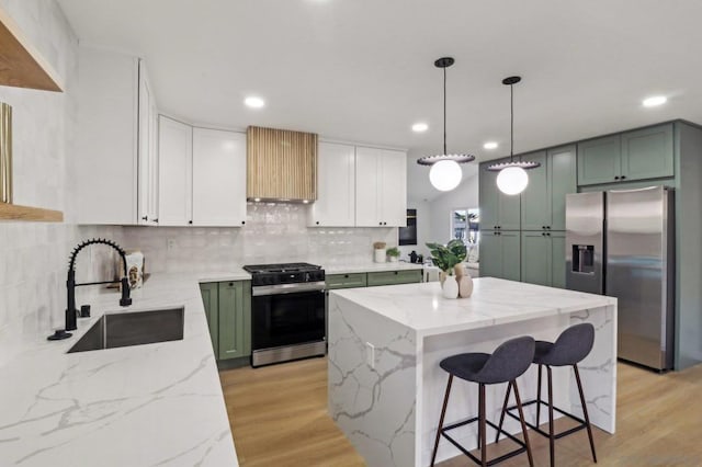 kitchen featuring sink, light stone counters, green cabinetry, a center island, and stainless steel appliances