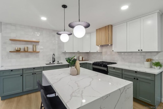 kitchen with sink, white cabinets, black range with gas stovetop, light stone counters, and light hardwood / wood-style floors