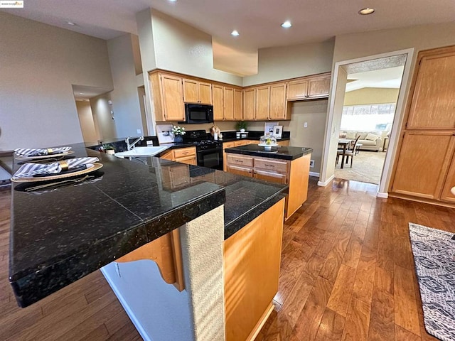 kitchen featuring wood-type flooring, sink, kitchen peninsula, and black appliances