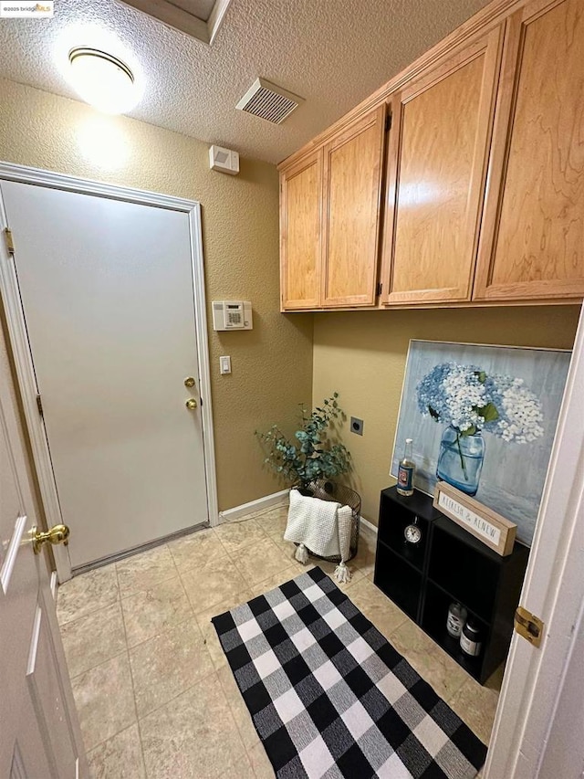 laundry area featuring cabinets, electric dryer hookup, and a textured ceiling