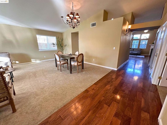 dining area featuring dark hardwood / wood-style flooring, lofted ceiling, a healthy amount of sunlight, and an inviting chandelier