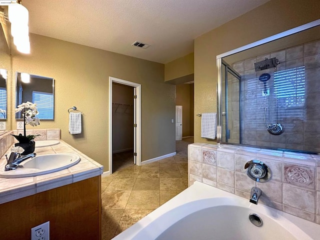 bathroom with tile patterned floors, vanity, plus walk in shower, and a textured ceiling