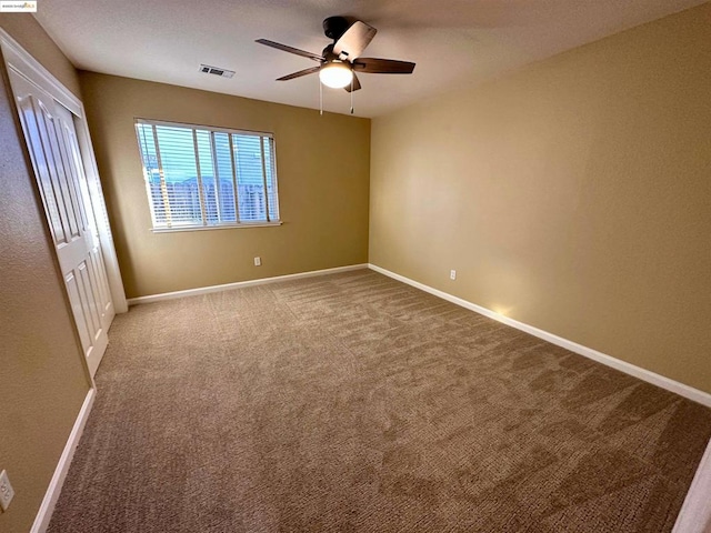 carpeted spare room featuring ceiling fan