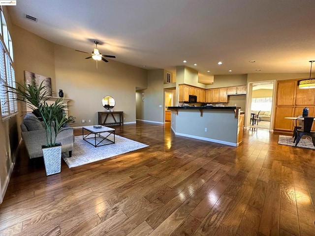 living room featuring vaulted ceiling, dark hardwood / wood-style floors, and ceiling fan