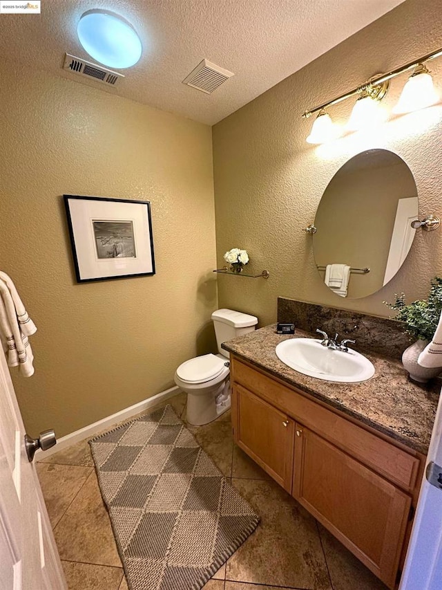 bathroom with vanity, toilet, tile patterned flooring, and a textured ceiling