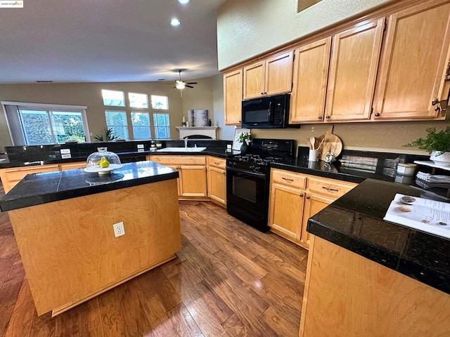 kitchen featuring sink, a center island, kitchen peninsula, hardwood / wood-style floors, and black appliances