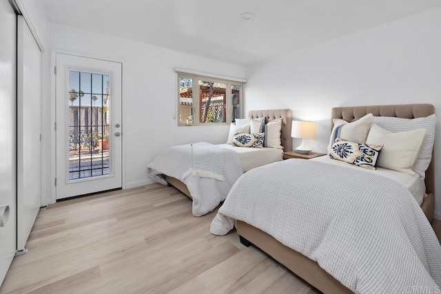 bedroom with a closet, light hardwood / wood-style floors, multiple windows, and access to outside