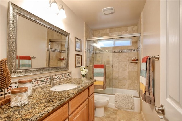 full bathroom featuring vanity, tile patterned flooring, shower / bath combination with glass door, and toilet