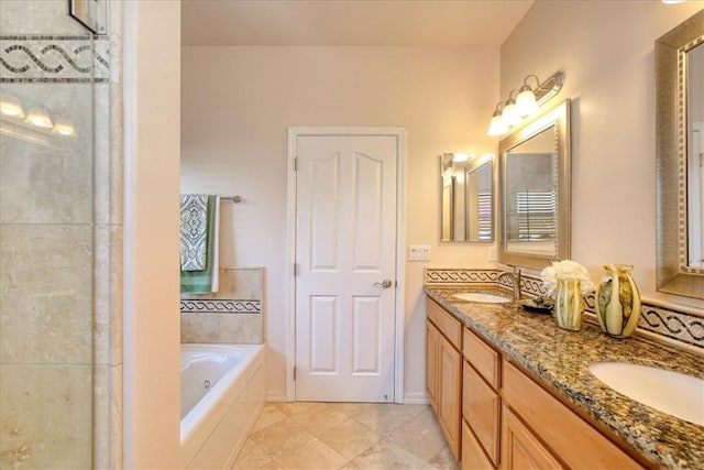 bathroom with tile patterned floors, vanity, and tiled bath