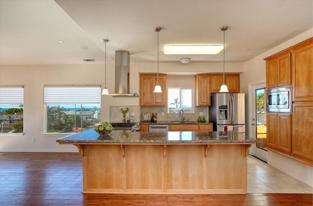 kitchen with sink, appliances with stainless steel finishes, a kitchen breakfast bar, a center island, and extractor fan