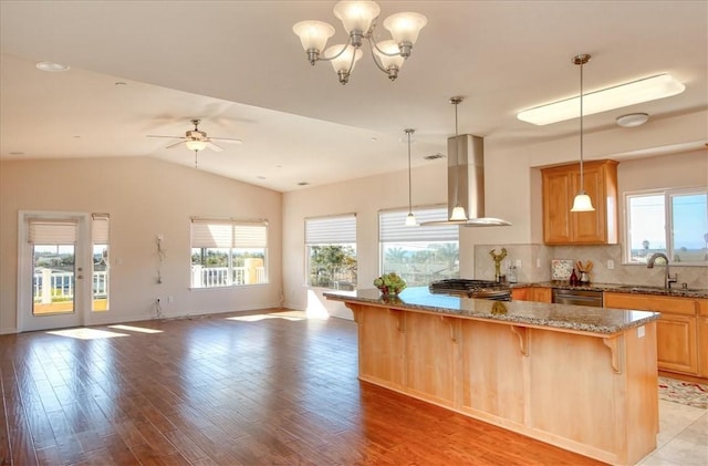 kitchen featuring island range hood, decorative light fixtures, sink, a kitchen breakfast bar, and stove