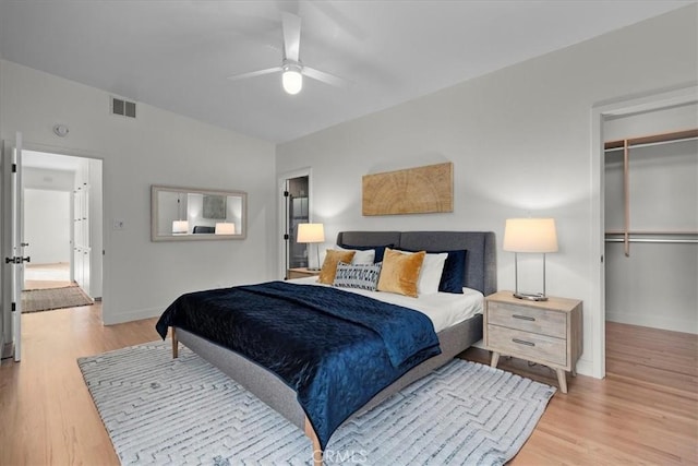 bedroom with vaulted ceiling, light hardwood / wood-style flooring, a spacious closet, ceiling fan, and a closet