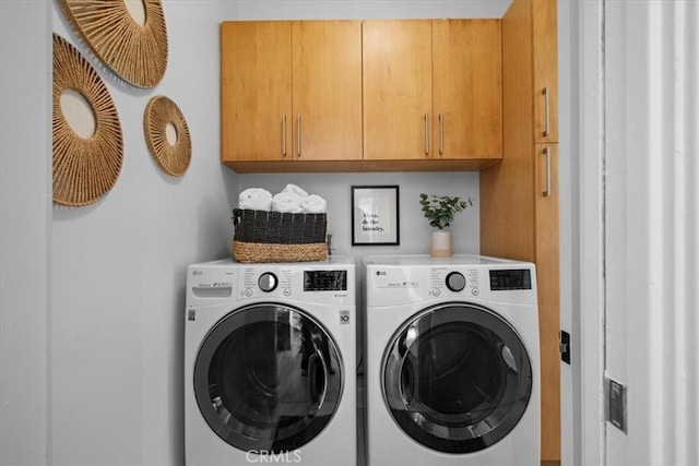 clothes washing area featuring cabinets and washing machine and clothes dryer