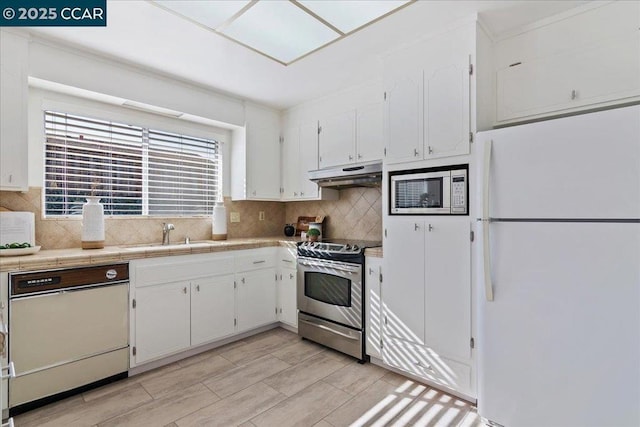 kitchen featuring appliances with stainless steel finishes, white cabinetry, sink, decorative backsplash, and tile counters