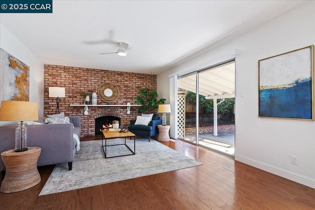 living room featuring ceiling fan, hardwood / wood-style floors, and a brick fireplace