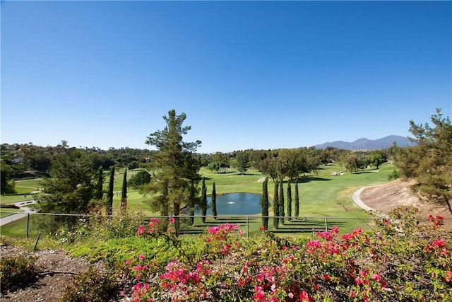 view of home's community featuring fence, a lawn, and a water and mountain view