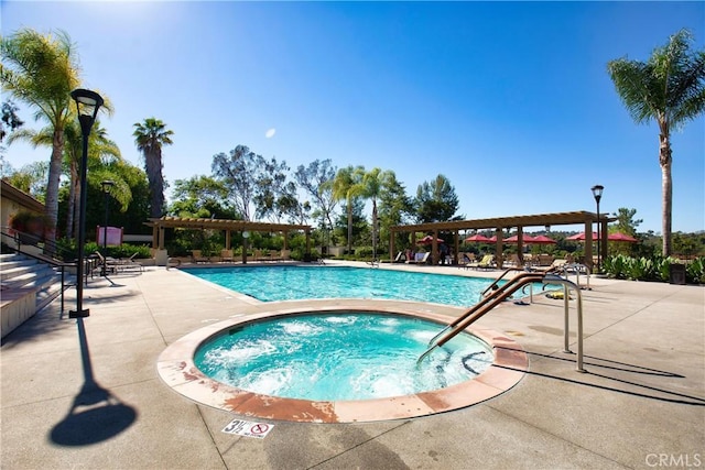 view of swimming pool featuring a community hot tub, a pergola, and a patio