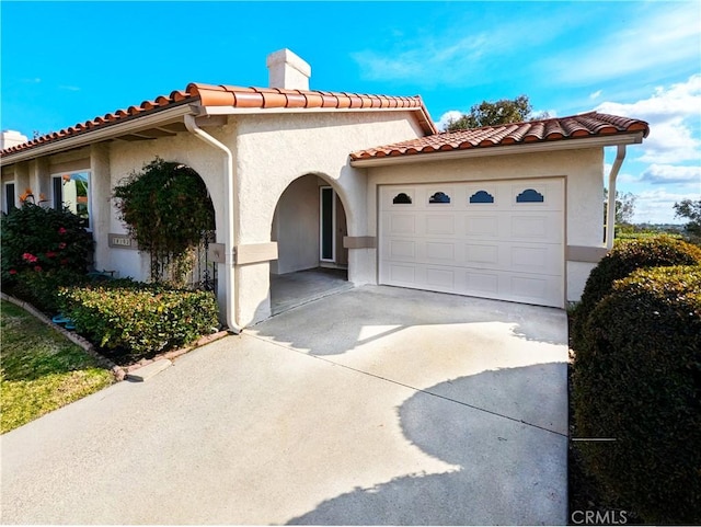 mediterranean / spanish house featuring a garage, a tile roof, driveway, and stucco siding