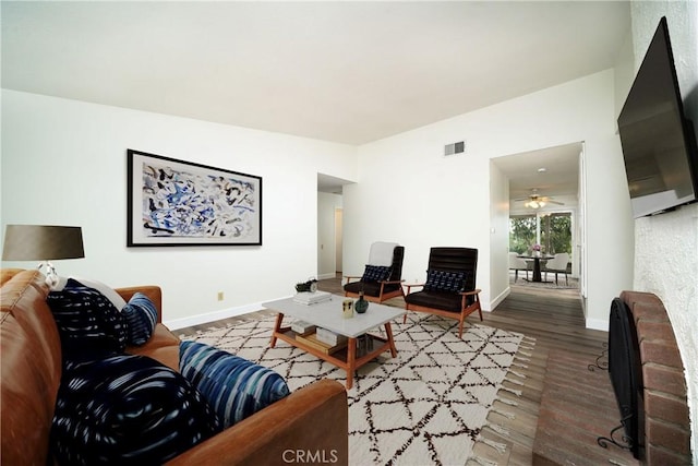 living area with dark wood-type flooring, visible vents, and baseboards