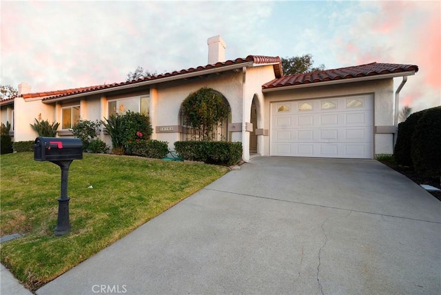 mediterranean / spanish house featuring a garage and a lawn