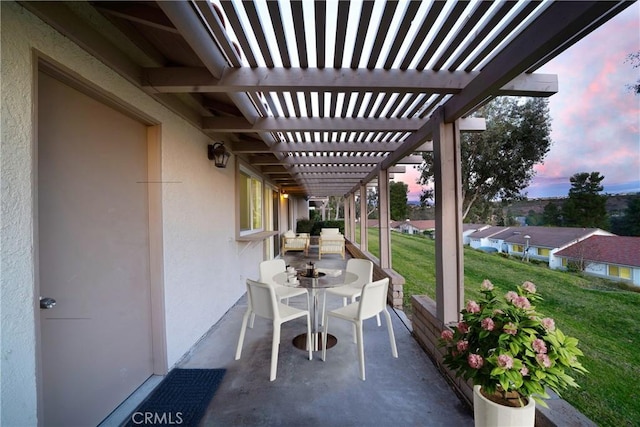 patio terrace at dusk featuring a pergola and a lawn