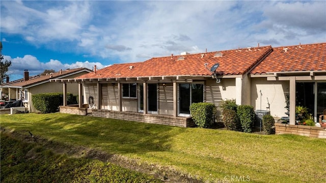 back of house with a lawn, a tiled roof, and stucco siding