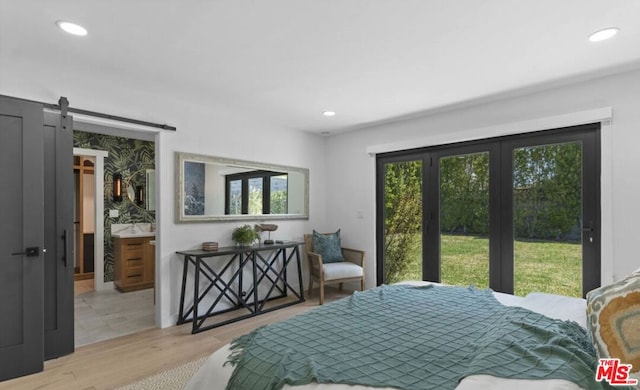 bedroom with a barn door, a spacious closet, and light hardwood / wood-style flooring