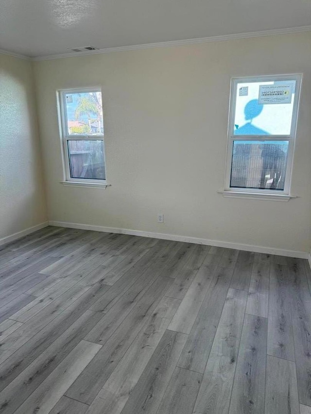 spare room featuring crown molding and light hardwood / wood-style flooring