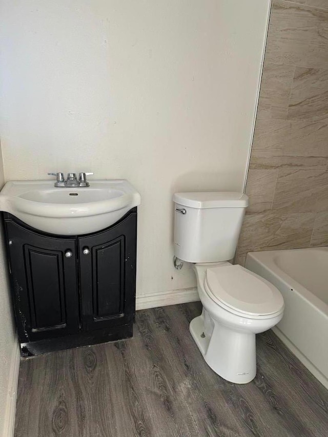 bathroom featuring hardwood / wood-style flooring, vanity, toilet, and a tub