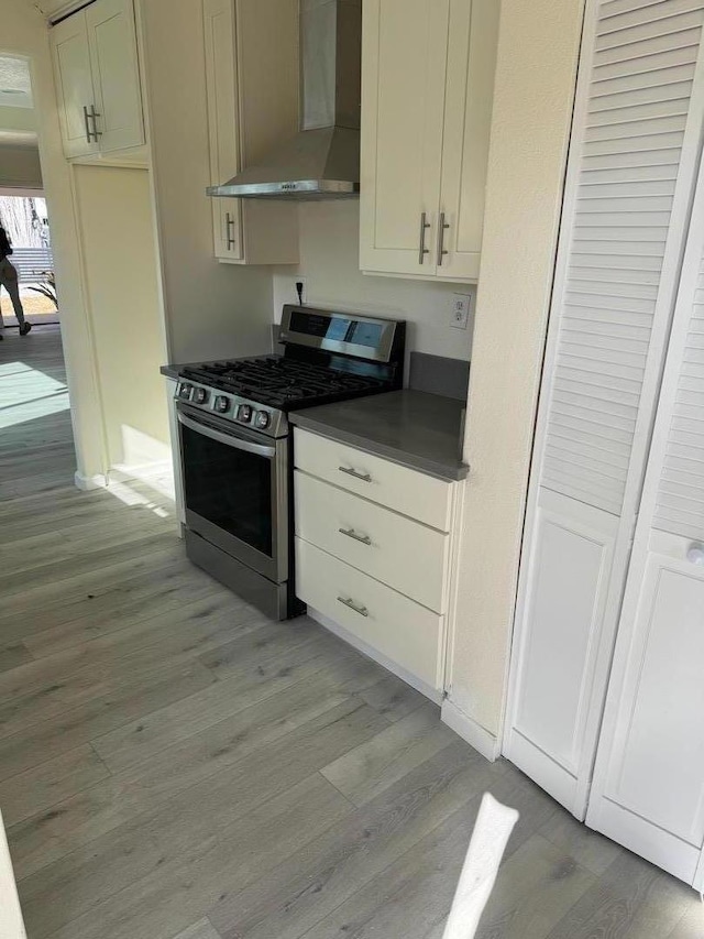 kitchen featuring stainless steel range with gas cooktop, light hardwood / wood-style flooring, and wall chimney range hood