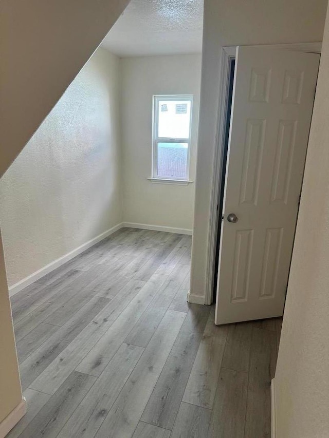 bonus room featuring a textured ceiling and light hardwood / wood-style flooring