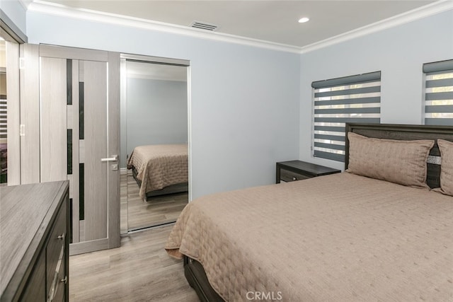 bedroom featuring ornamental molding, light wood-type flooring, and a closet