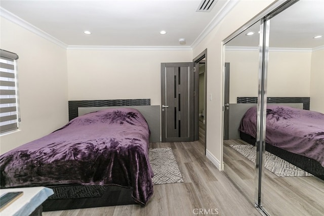 bedroom featuring crown molding, light hardwood / wood-style flooring, and a closet