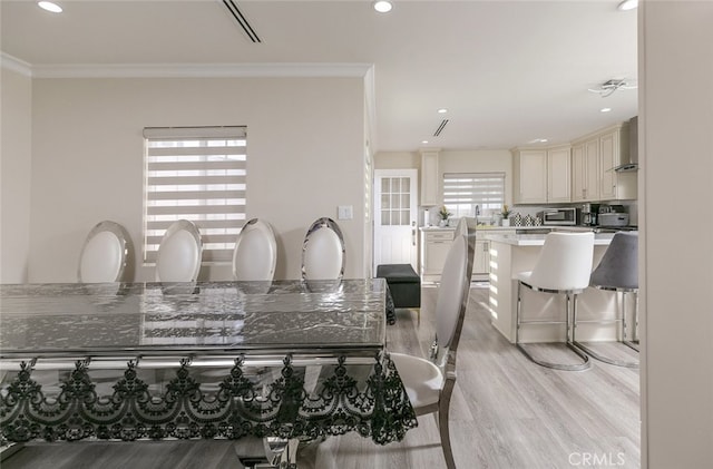 dining space featuring crown molding and light hardwood / wood-style floors