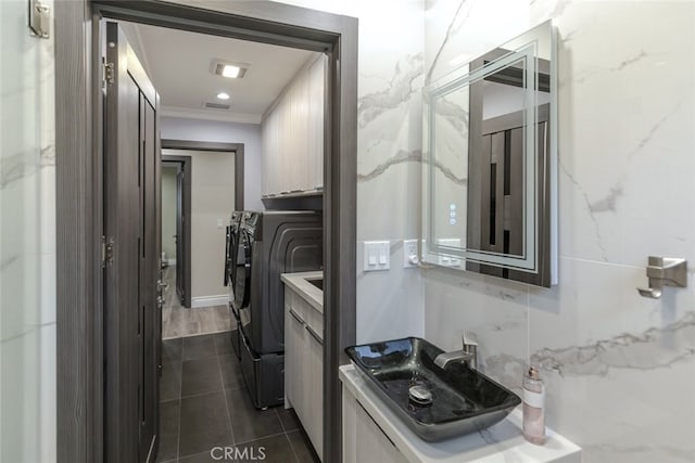 laundry area featuring crown molding, sink, dark tile patterned flooring, and washer and clothes dryer