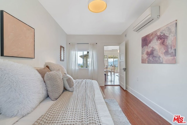 bedroom with an AC wall unit and hardwood / wood-style floors