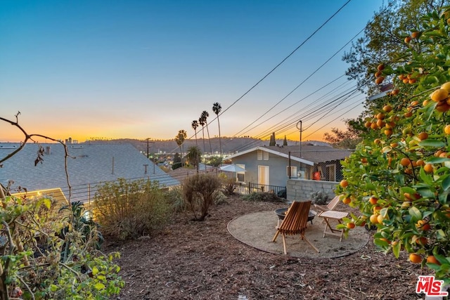 yard at dusk featuring a patio and a water view