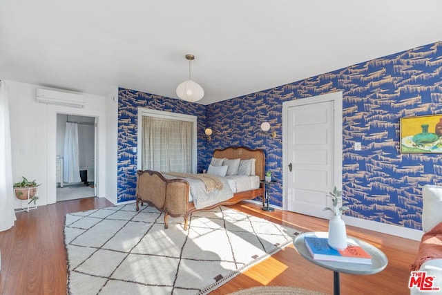 bedroom with hardwood / wood-style flooring and a wall unit AC