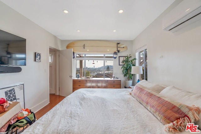 bedroom with a wall mounted air conditioner and light wood-type flooring