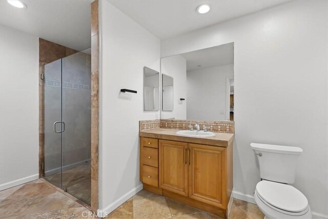 bathroom with vanity, toilet, a shower with door, and decorative backsplash