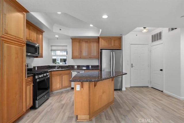 kitchen with a kitchen island, appliances with stainless steel finishes, a breakfast bar area, dark stone counters, and ornamental molding