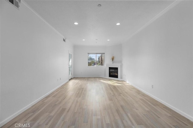 unfurnished living room featuring crown molding and light hardwood / wood-style floors